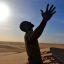 Man experiencing the freedom of the Sahara Desert as the sun looms above his head. Sir Driver Tours. Private tour.