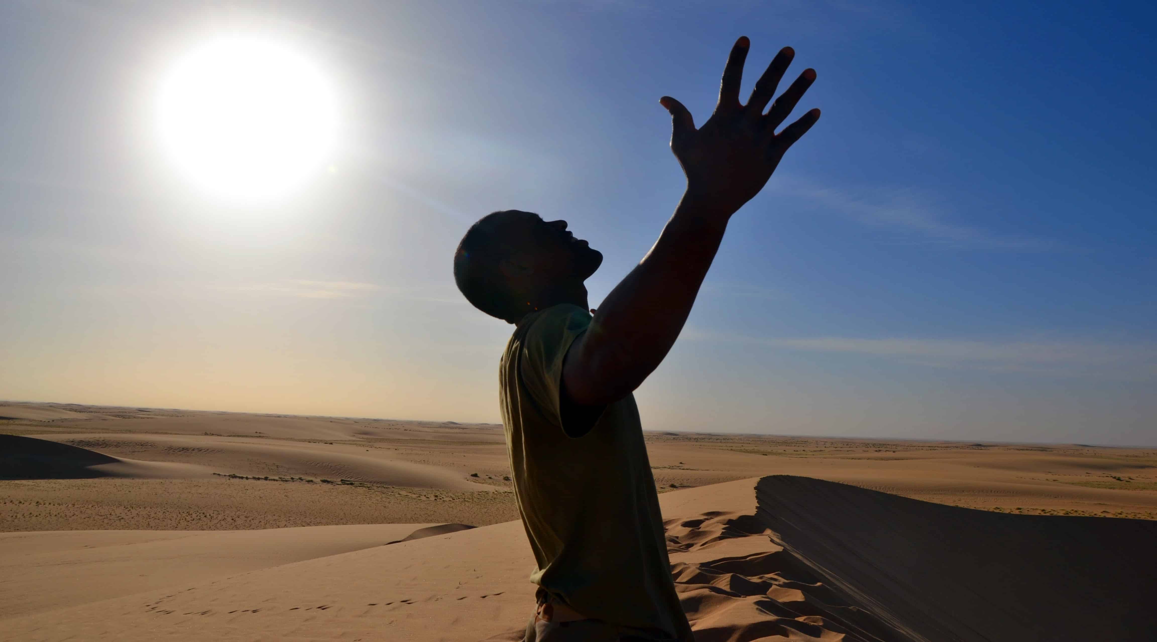 Man experiencing the freedom of the Sahara Desert as the sun looms above his head. Sir Driver Tours. Private tour.